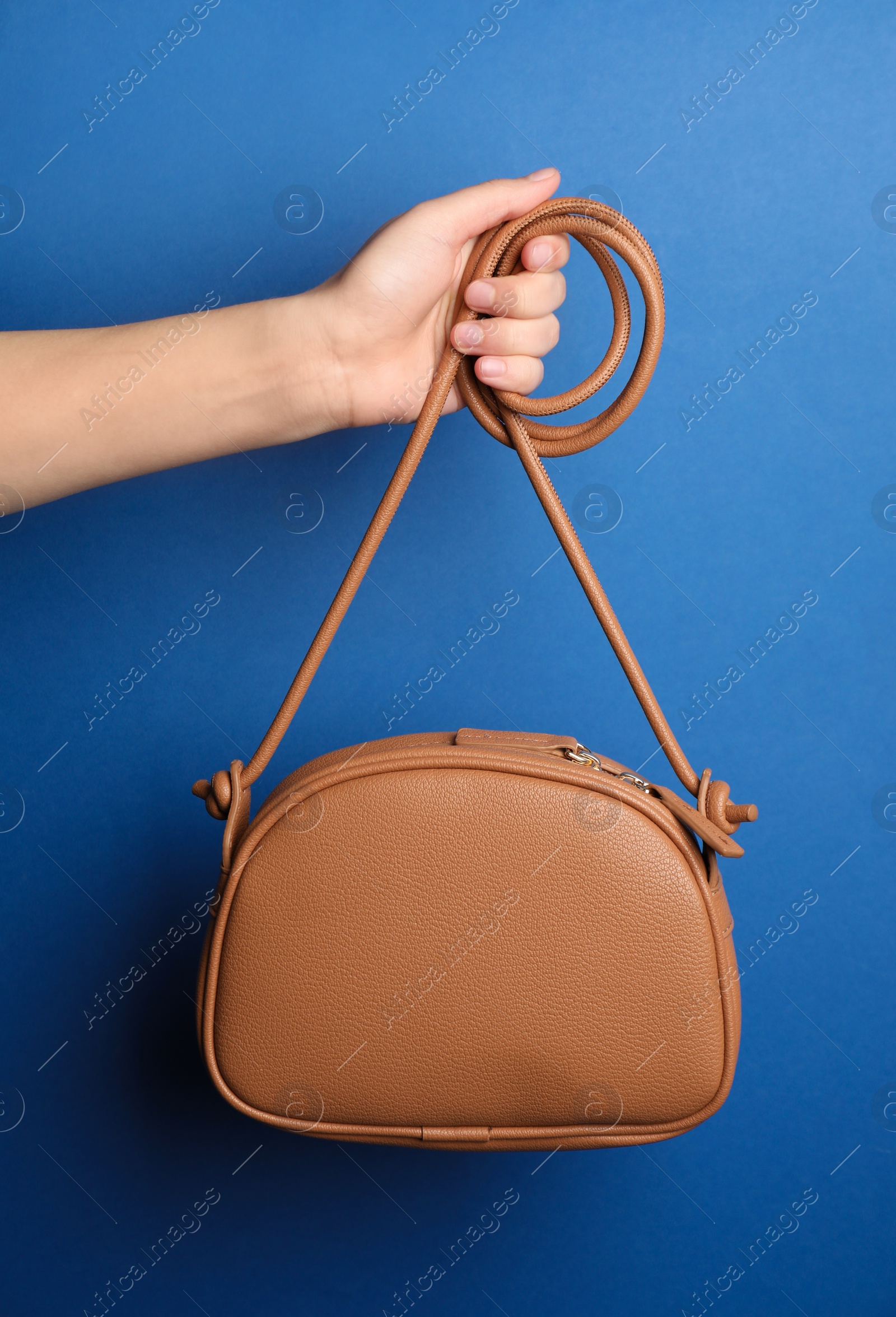 Photo of Woman holding stylish bag on blue background, closeup