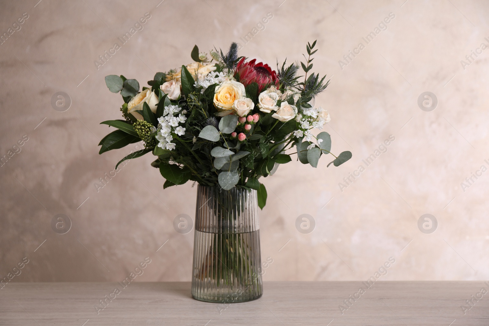 Photo of Beautiful bouquet with roses on wooden table