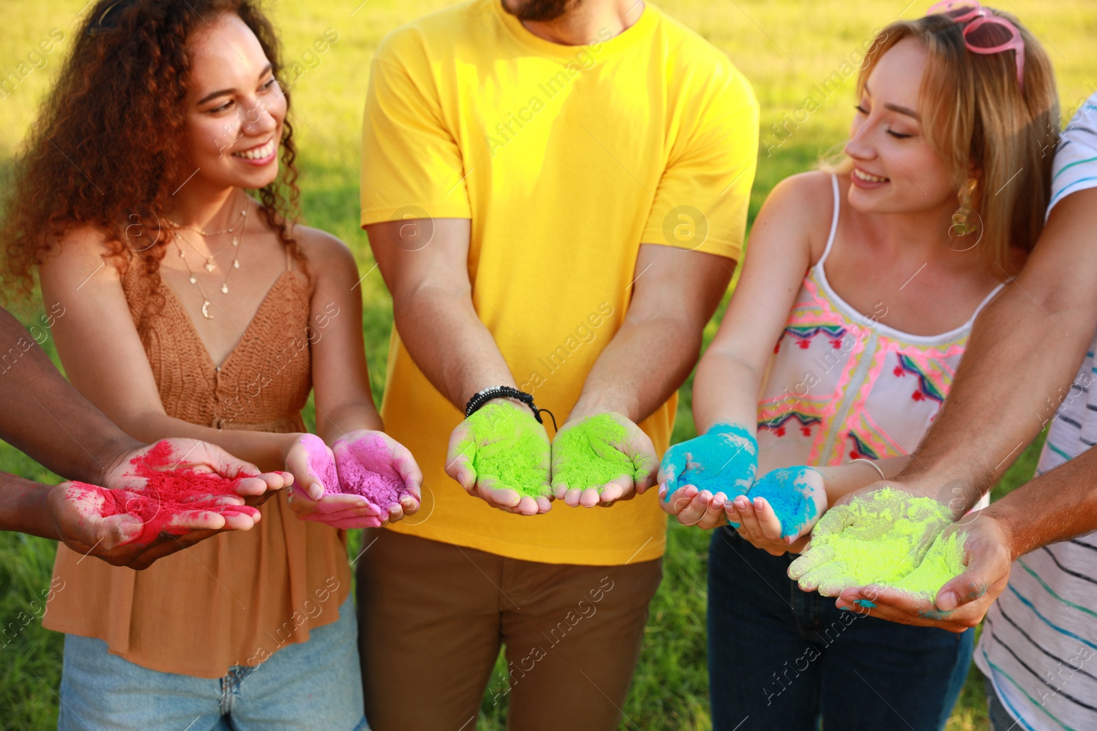 Photo of Friends with colorful powder dyes outdoors. Holi festival celebration