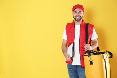 Photo of Courier with thermo bag on yellow background, space for text. Food delivery service