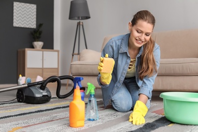 Young woman cleaning carpet at home