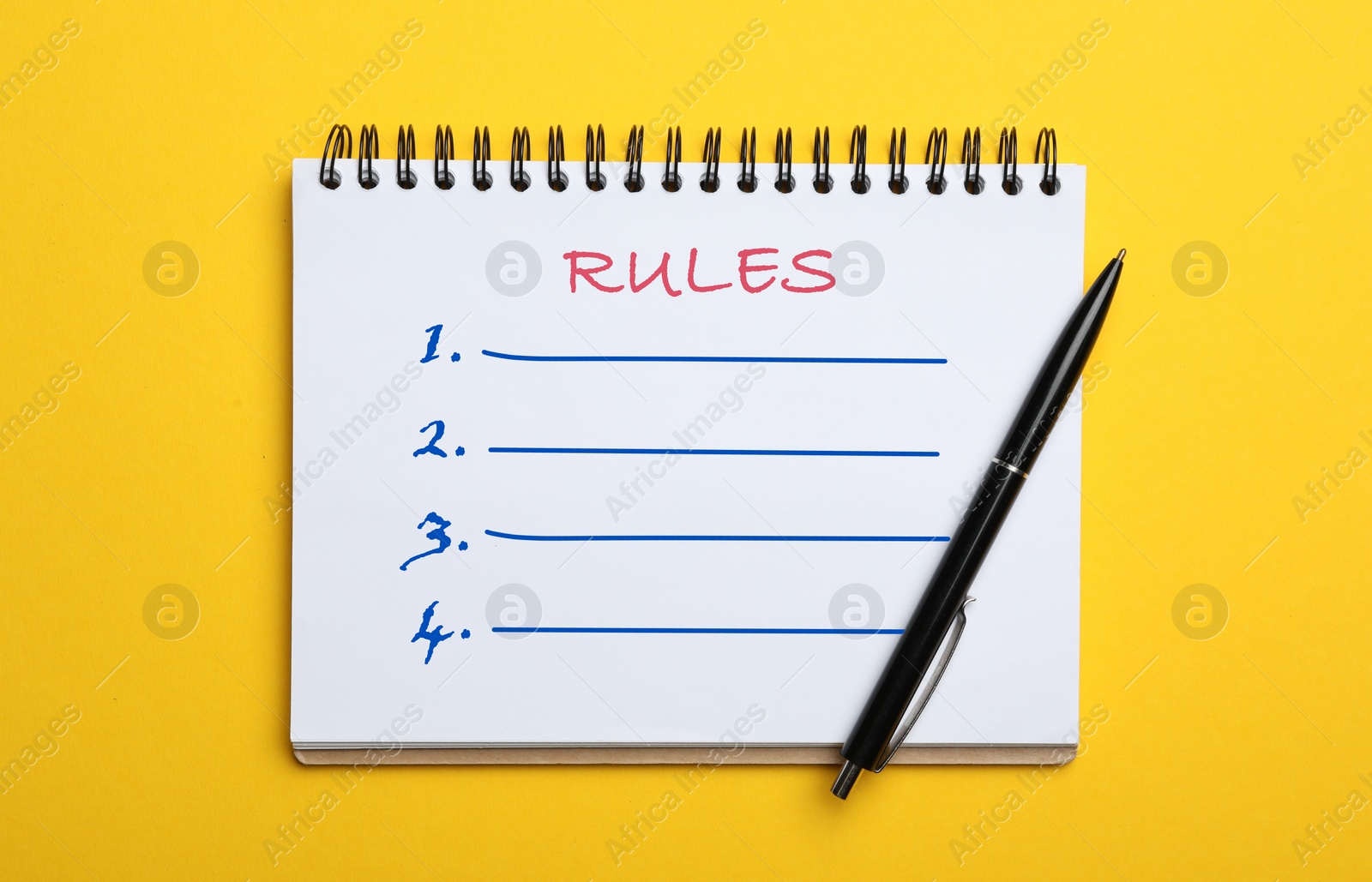 Image of Notebook with list of rules and pen on yellow background, top view