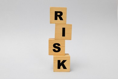 Photo of Stack of wooden cubes with word Risk on light grey background