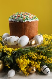 Traditional Easter cake with sprinkles, painted eggs and beautiful spring flowers on white wooden table