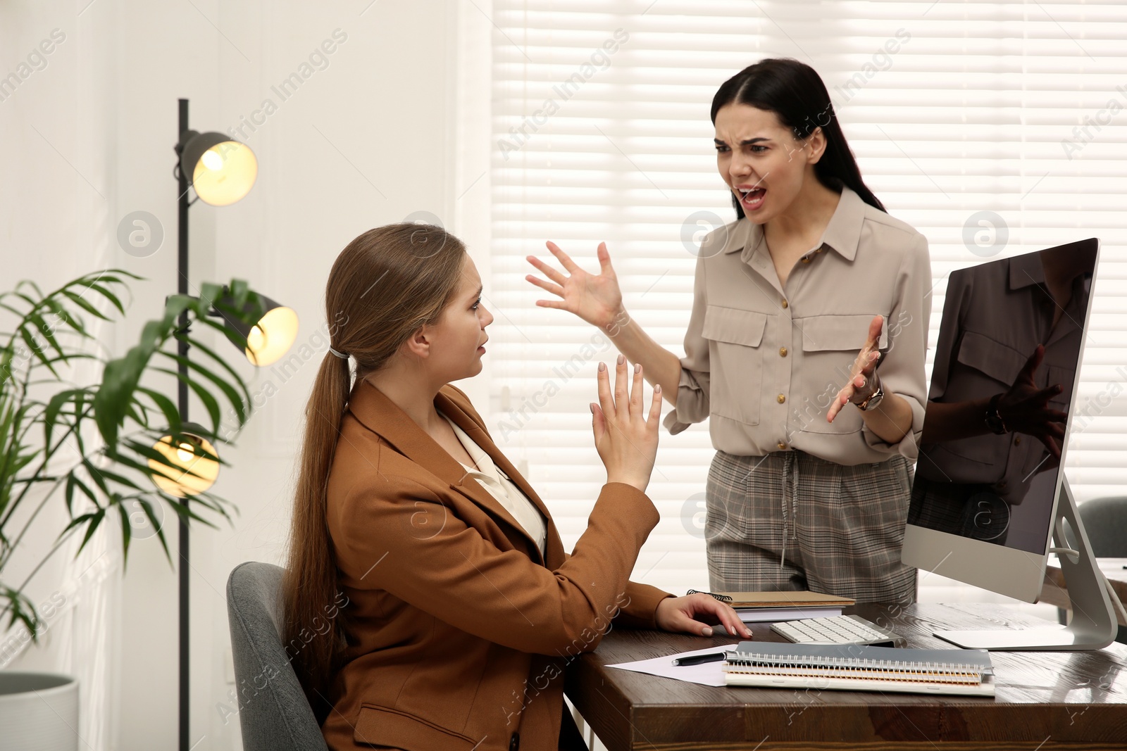 Photo of Boss screaming at employee in office. Toxic work environment