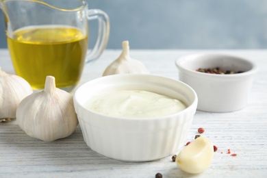 Photo of Fresh garlic and bowl of sauce on white wooden table