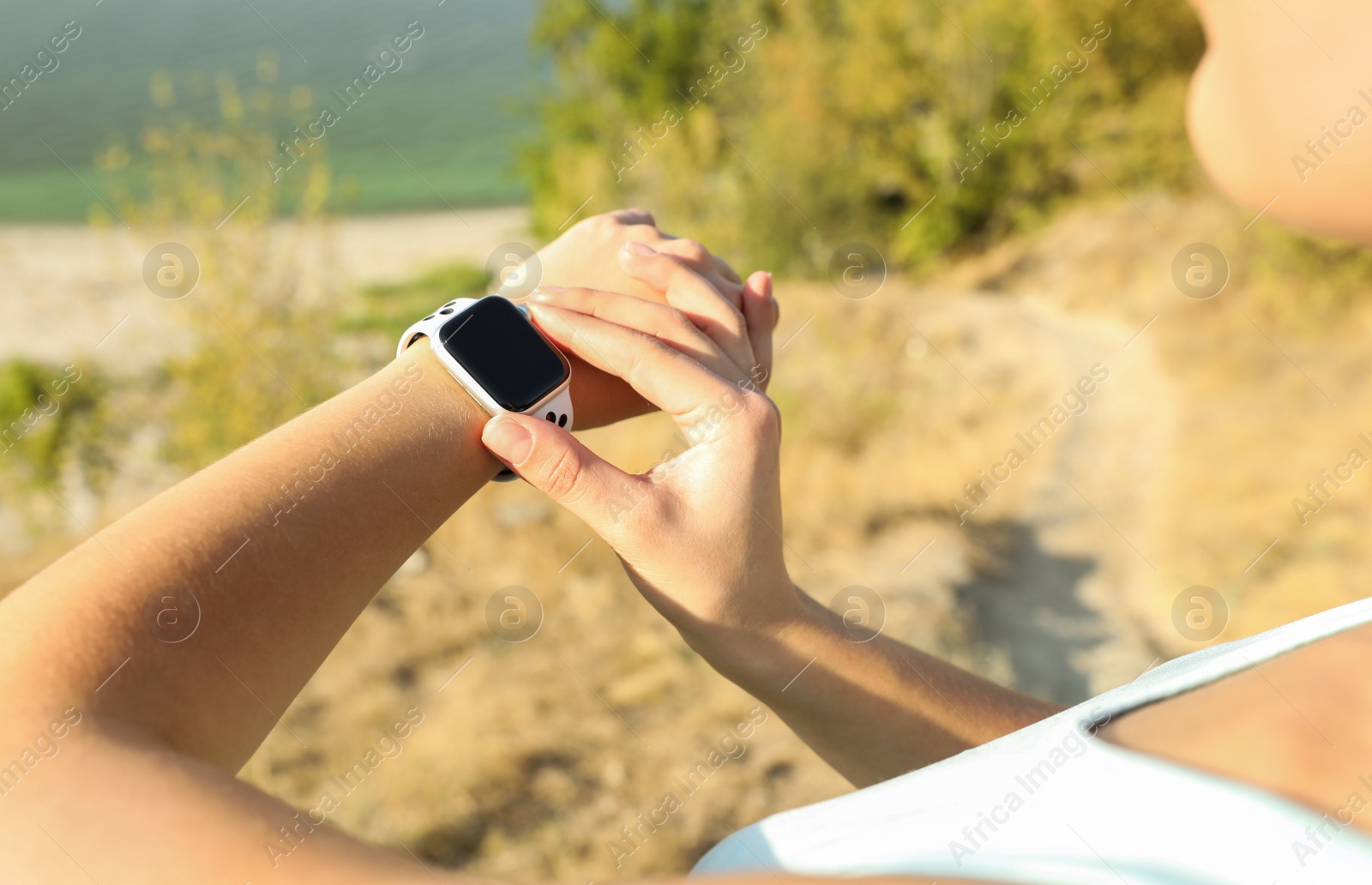 Photo of Woman checking modern smart watch during training outdoors, closeup