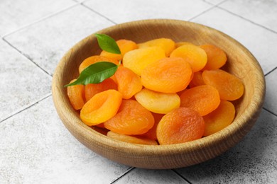 Wooden bowl of tasty apricots on white tiled table. Dried fruits