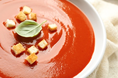 Photo of Bowl with fresh homemade tomato soup on table, closeup