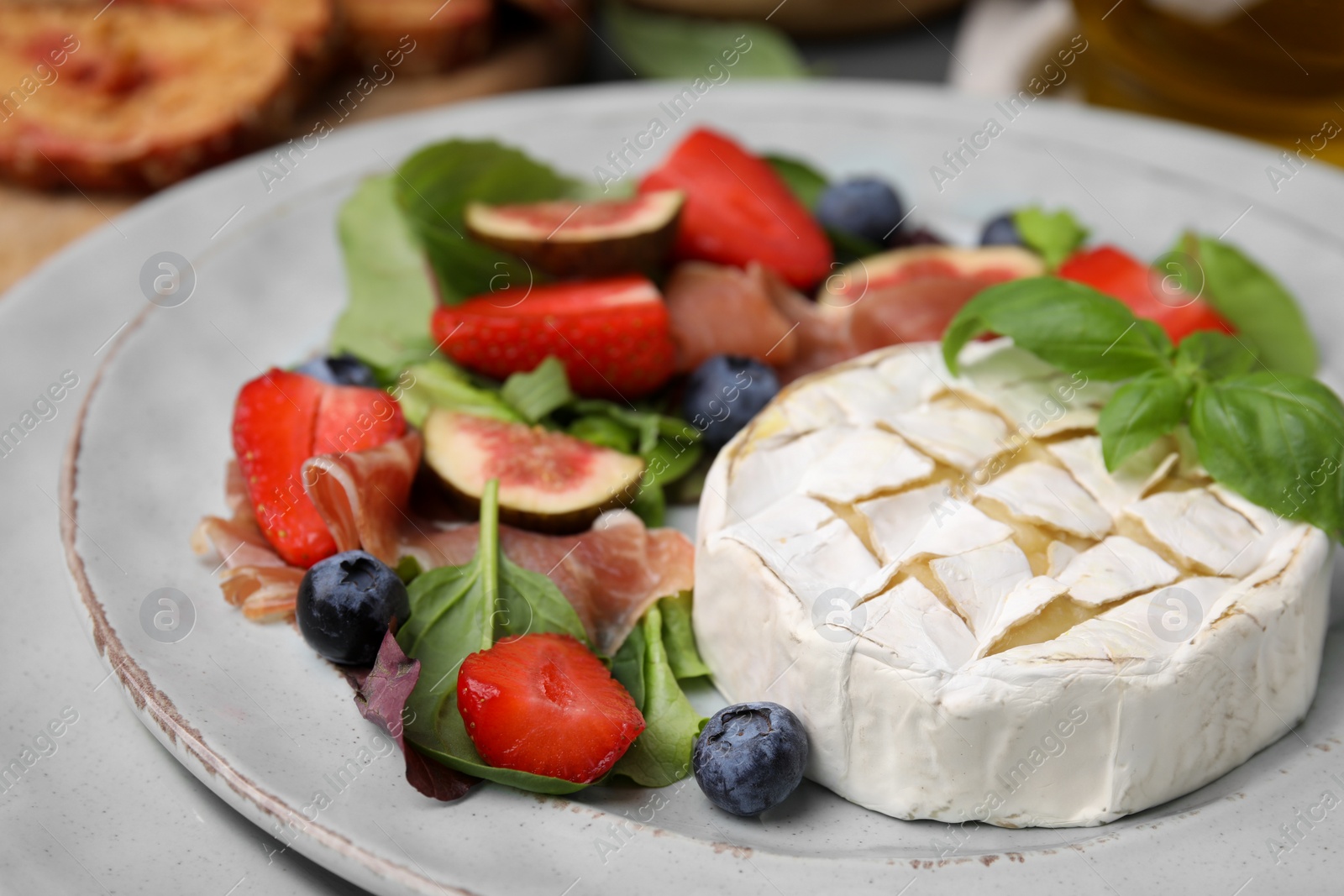 Photo of Delicious salad with brie cheese, blueberries, figs and strawberries on plate, closeup