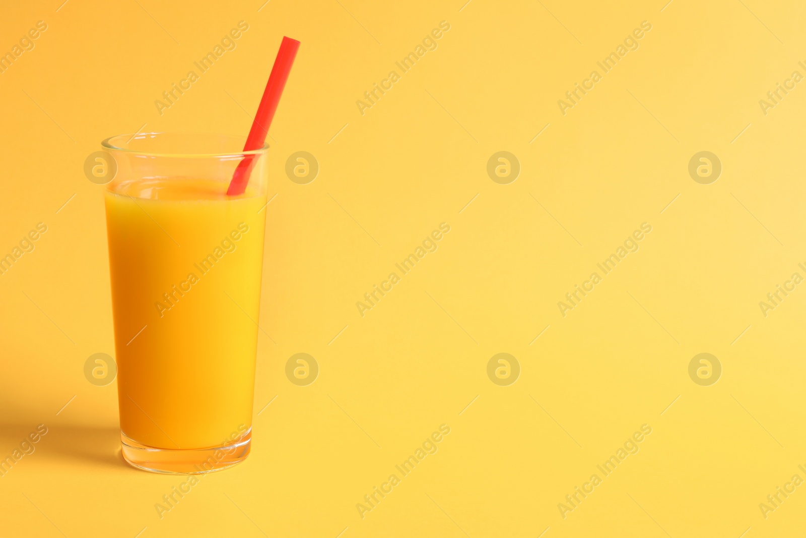 Photo of Glass of orange juice on color background