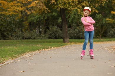 Photo of Cute girl roller skating in autumn park. Space for text