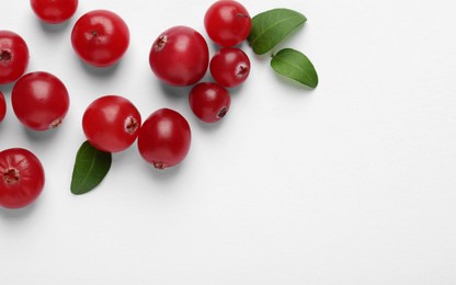 Photo of Fresh ripe cranberries and green leaves on white background, flat lay. Space for text