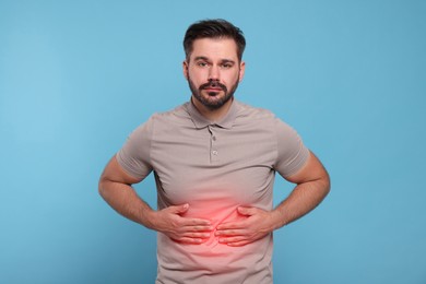 Man suffering from stomach pain on light blue background