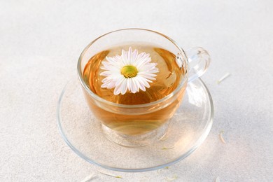 Photo of Glass cup of delicious chamomile tea on white table