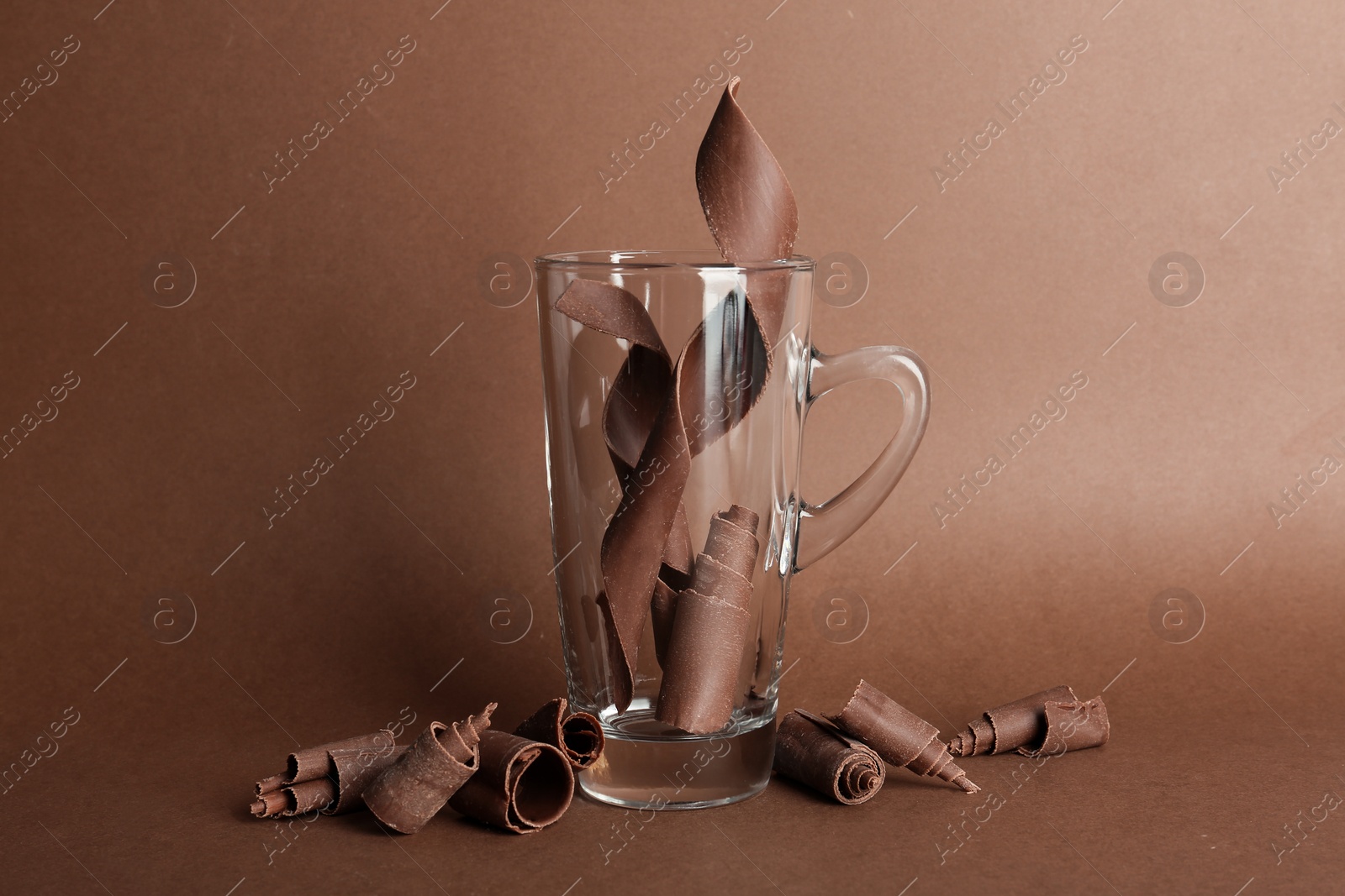 Photo of Glass cup and chocolate curls on color background