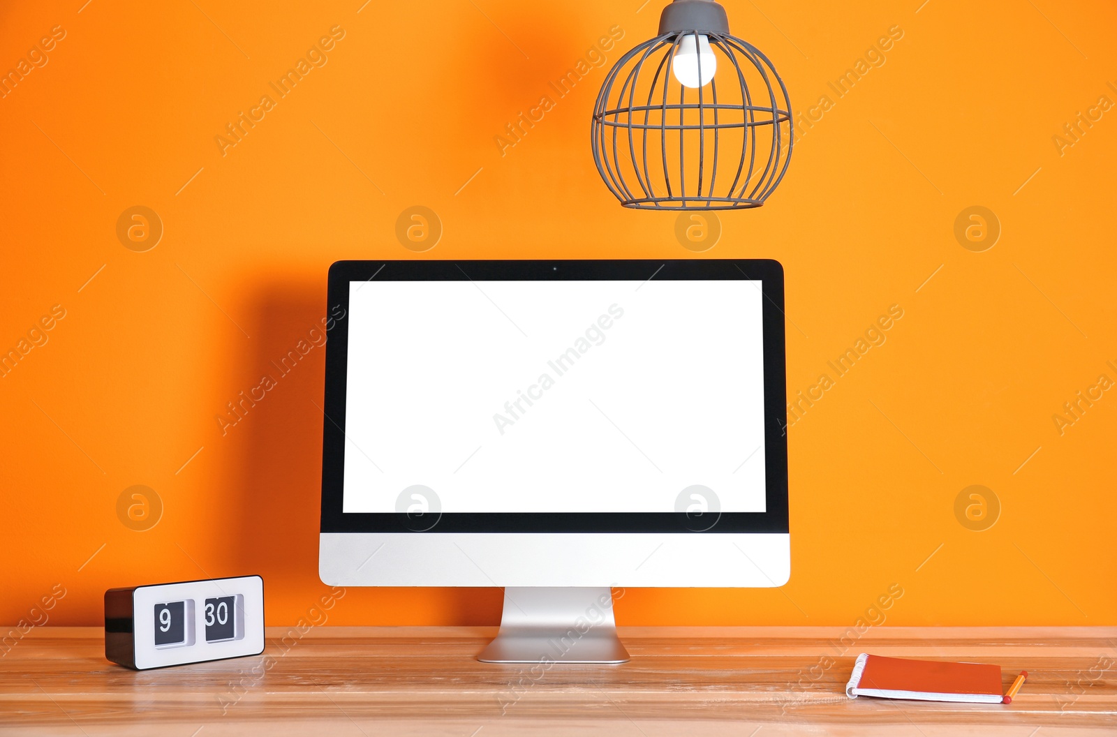 Photo of Modern computer monitor on table against color wall. Mock up with space for text