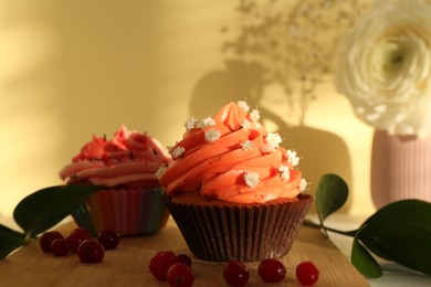 Photo of Delicious cupcake with bright cream and flowers on wooden table