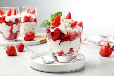 Delicious strawberries with whipped cream served on light grey table