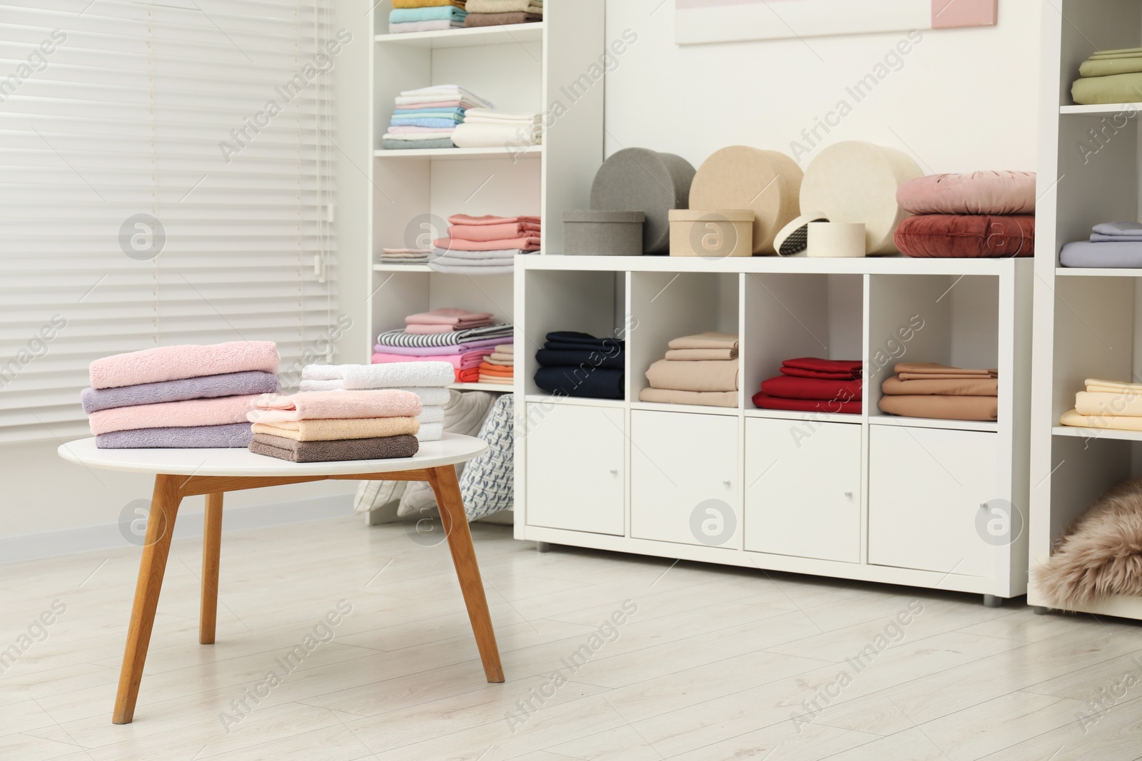 Photo of Stacked towels, decorative boxes and colorful bed linens in home textiles store