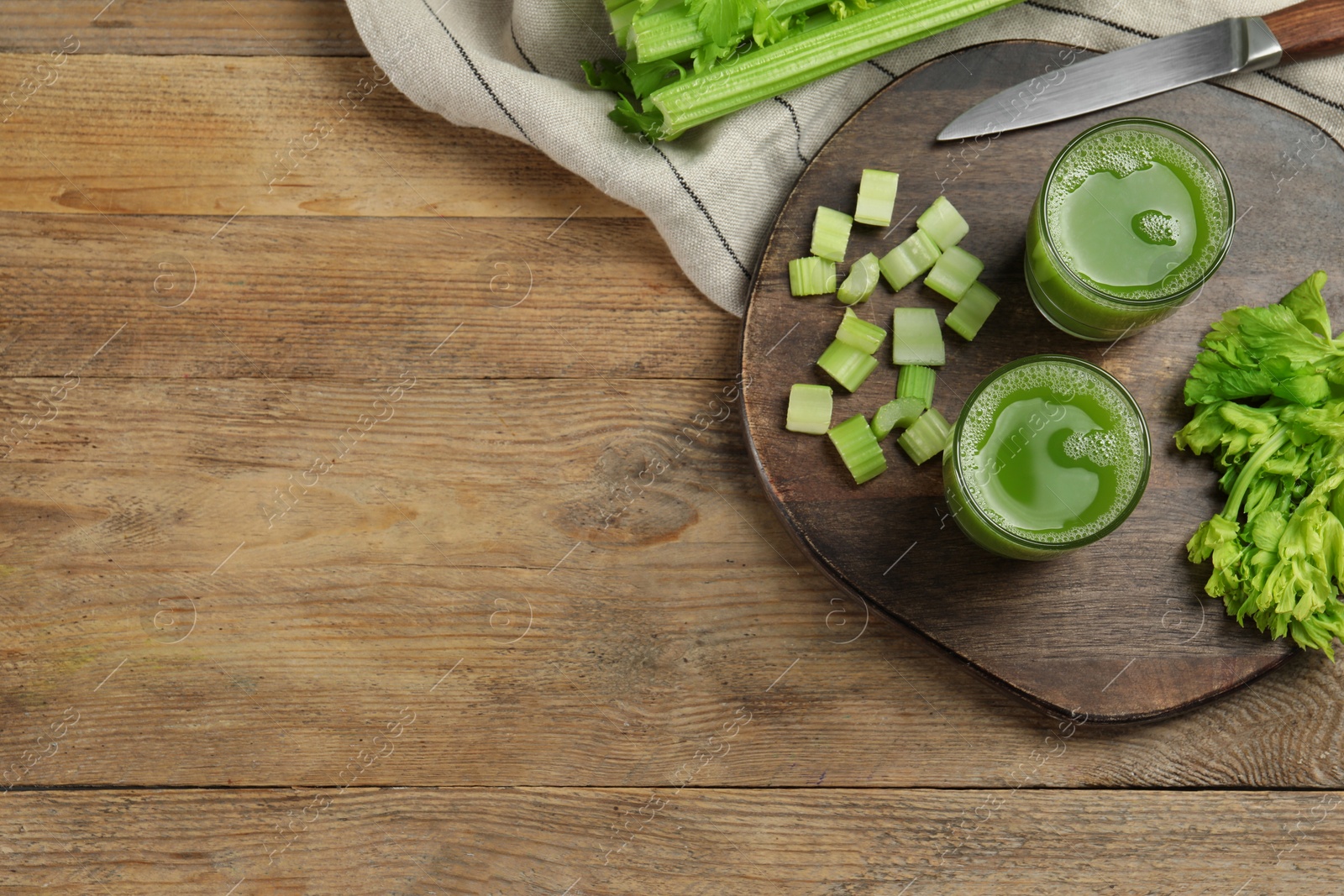 Photo of Glasses of delicious celery juice and vegetables on wooden table, flat lay. Space for text
