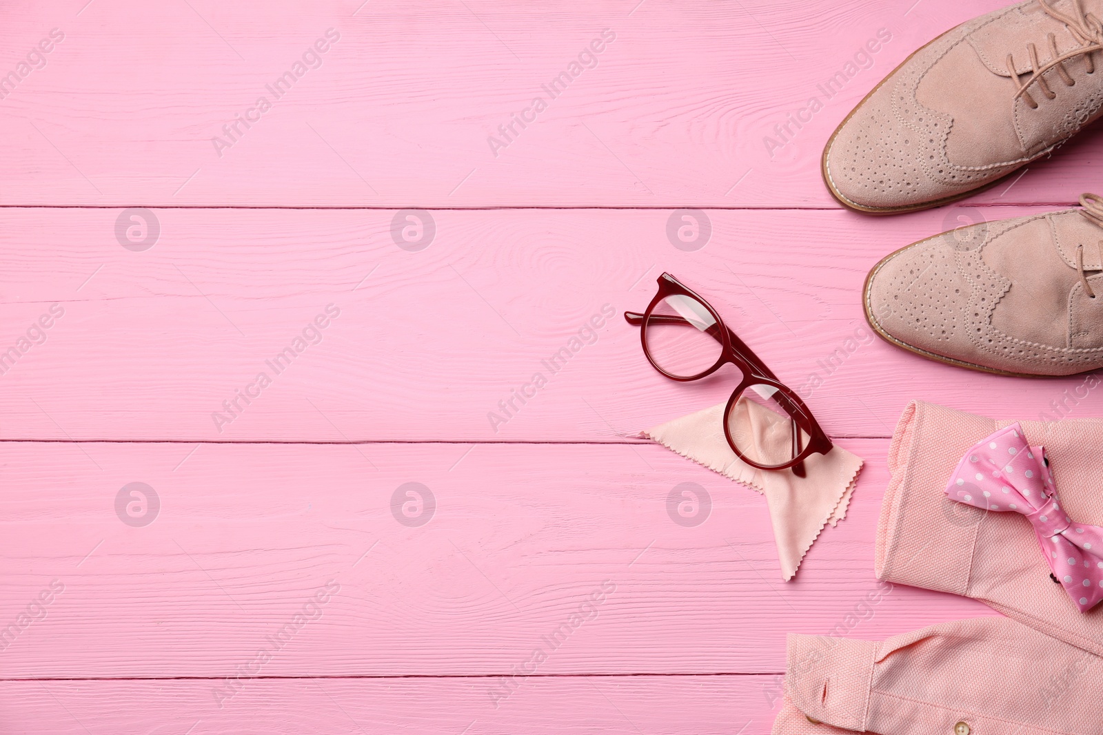 Photo of Flat lay composition with glasses and stylish bow tie on pink wooden background. Space for text