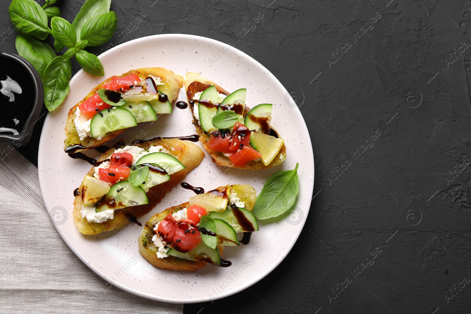 Photo of Delicious bruschettas with balsamic vinegar and toppings on black table, flat lay. Space for text