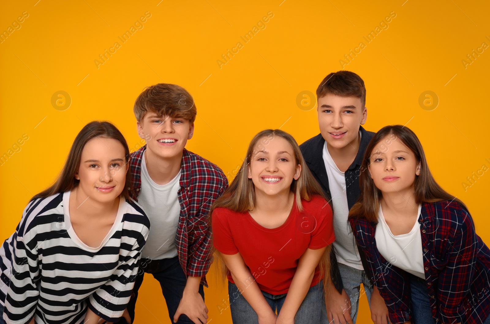 Photo of Group of happy teenagers on orange background