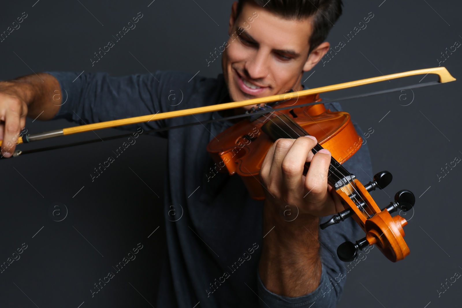 Photo of Happy man playing violin on black background, focus on hand