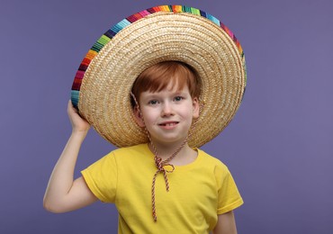 Photo of Cute boy in Mexican sombrero hat on violet background