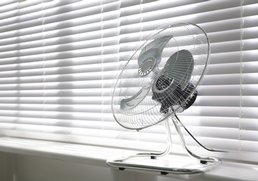 Photo of Modern electric fan on window sill indoors. Space for text