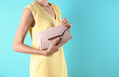 Young woman in stylish outfit with purse on color background, closeup