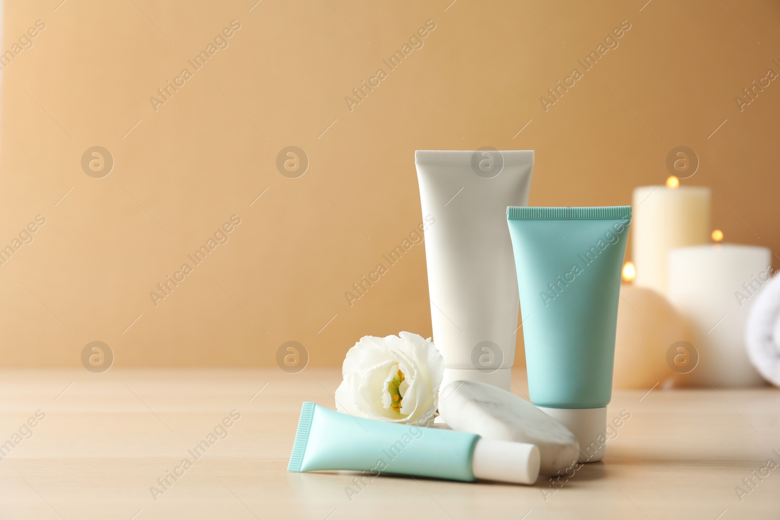 Photo of Cosmetic products, flower and spa stones on wooden table. Space for text