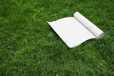 White karemat or fitness mat on green grass outdoors. Space for text