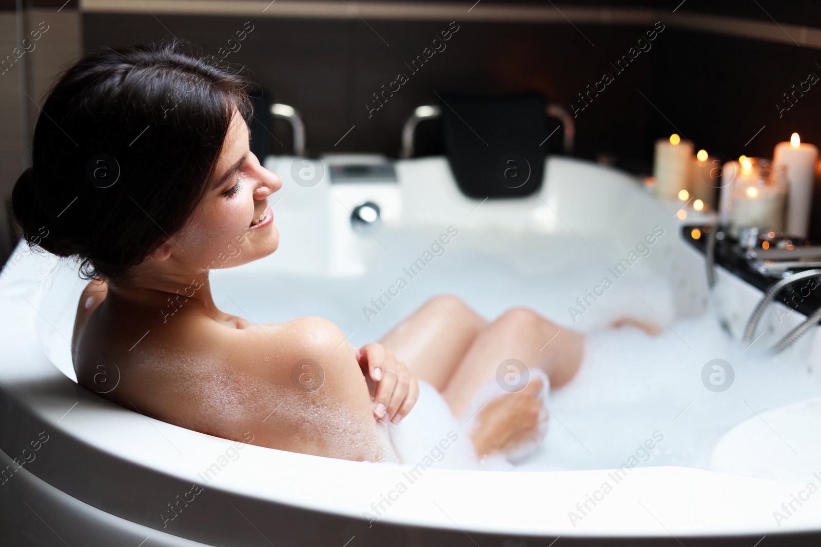 Photo of Happy beautiful woman taking bubble bath. Romantic atmosphere