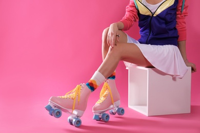 Young woman with retro roller skates on color background, closeup. Space for text
