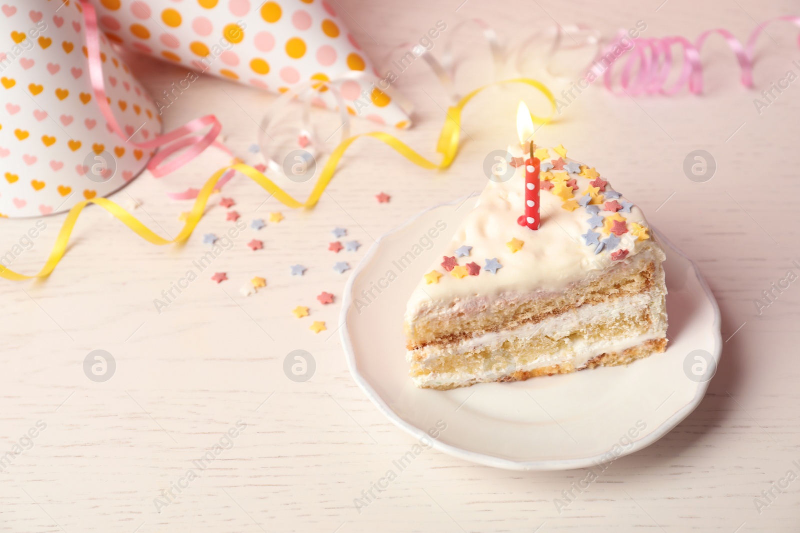 Photo of Slice of delicious birthday cake with candle on table