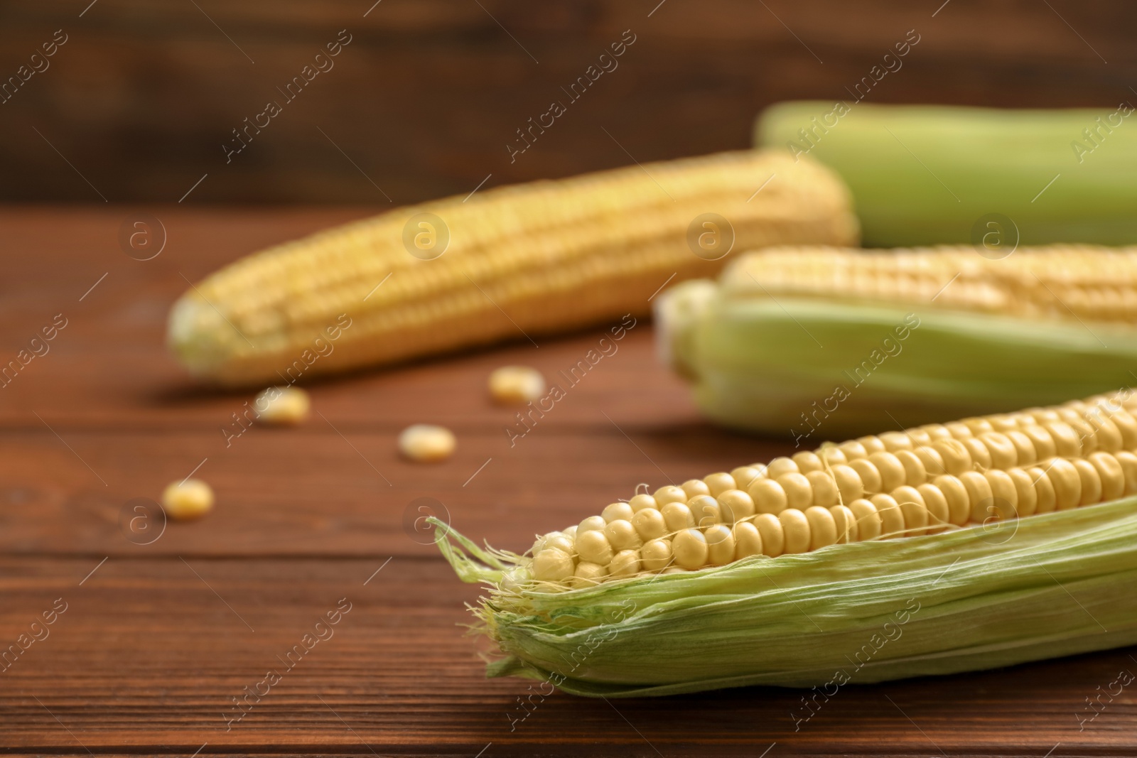 Photo of Tasty ripe corn cobs on wooden table