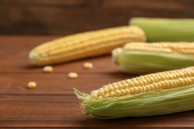 Tasty ripe corn cobs on wooden table