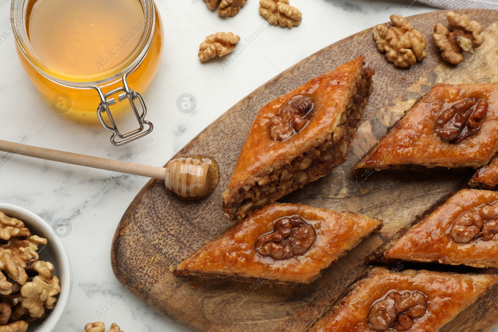 Photo of Delicious honey baklava with walnuts on white marble table, flat lay