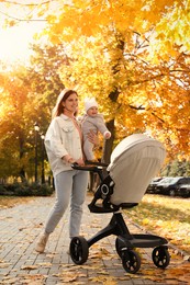 Photo of Happy mother walking with her daughter and stroller on city street