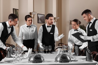 Photo of People setting table during professional butler courses in restaurant