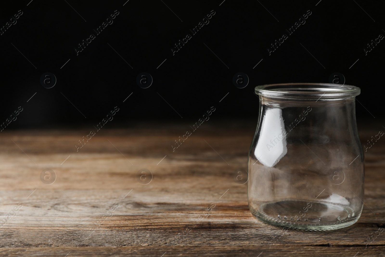 Photo of Empty glass jar on wooden table, space for text