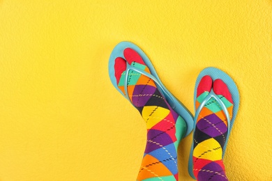 Photo of Woman wearing bright socks with flip-flops and space for design on color background