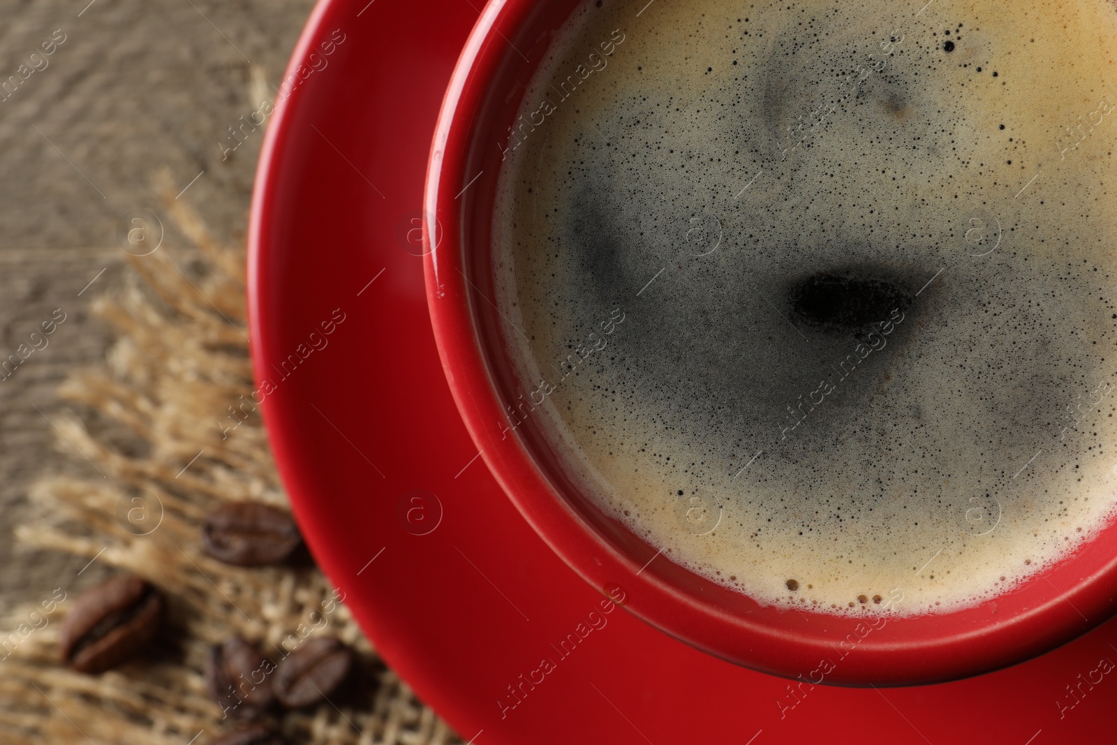 Photo of Cup of aromatic coffee on wooden table, top view