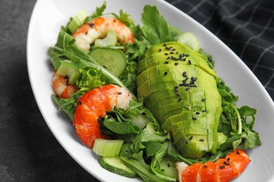 Photo of Delicious avocado salad with shrimps in bowl on grey table, closeup