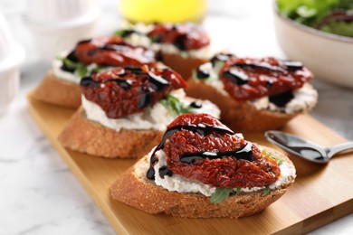 Photo of Delicious bruschettas with sun-dried tomatoes, cream cheese and balsamic vinegar on white table, closeup