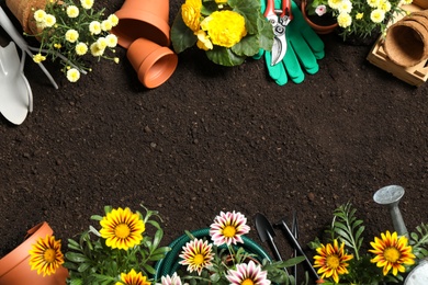 Photo of Flat lay composition with gardening equipment and flowers on soil, space for text