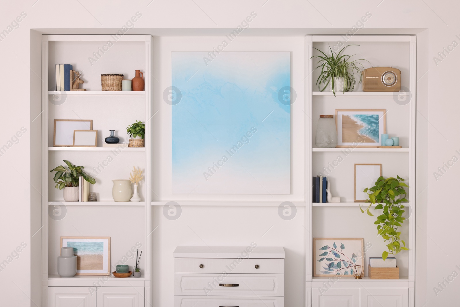 Photo of Interior design. Abstract picture and chest of drawers between shelves with accessories indoors