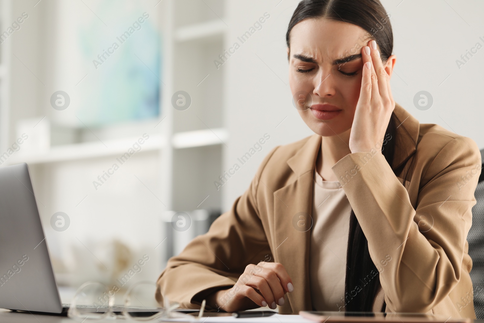 Photo of Woman suffering from headache at workplace in office, space for text